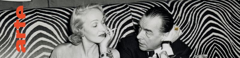 schwarz/weiß Bild einer Frau (Marlene Dietrich) und eines Mannes (Erich Maria Remarque) auf einer Couch.